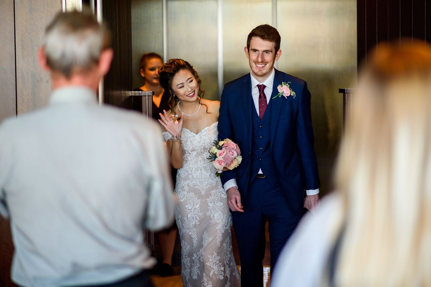 Wedding party walking through an elegant hallway with soft lighting and formal attire.