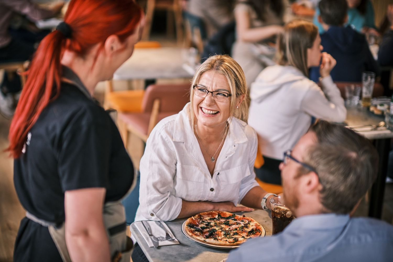 Diners enjoying meals and conversation at tables in a cozy restaurant setting.