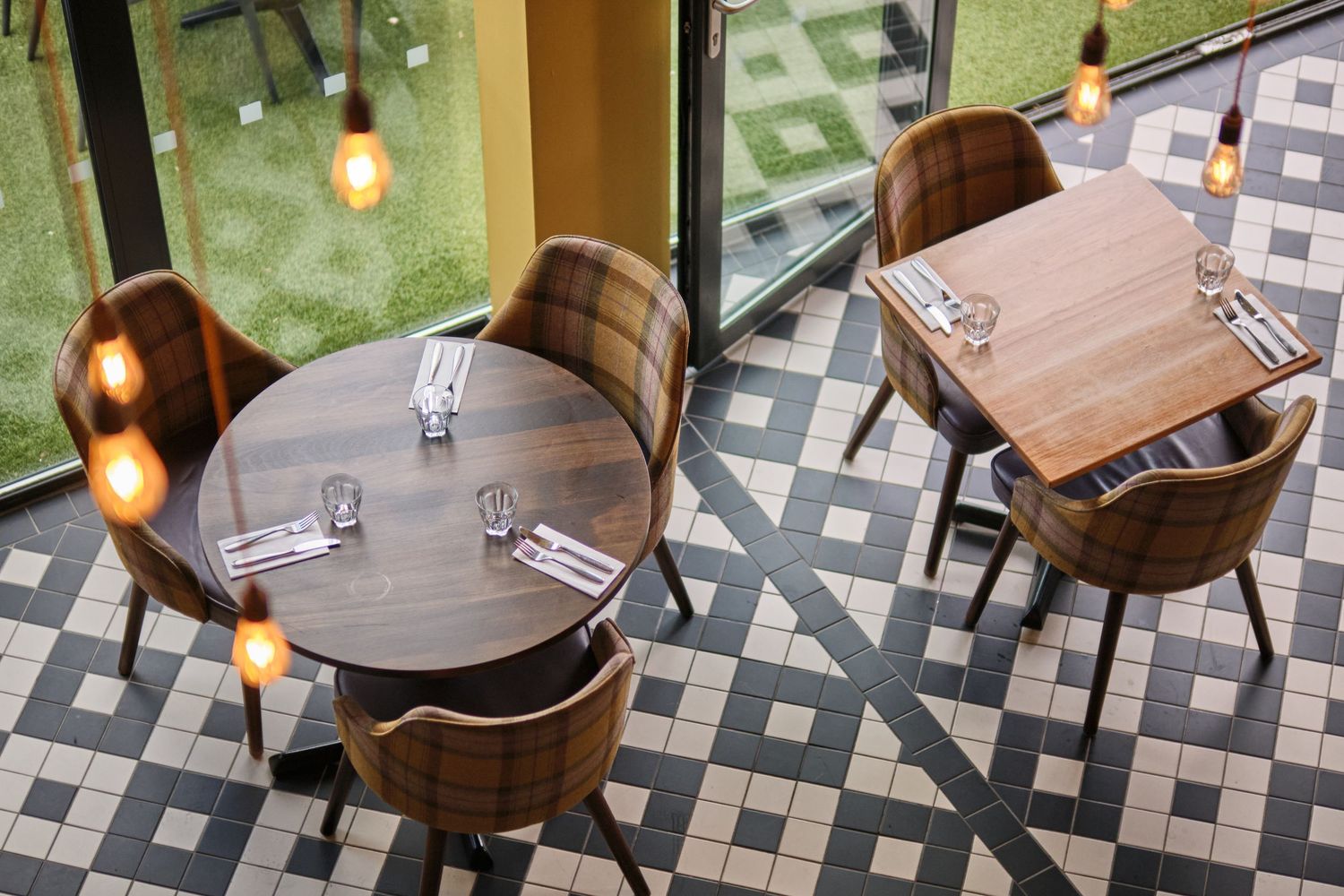 Modern restaurant interior featuring geometric patterned flooring and comfortable brown leather chairs.
