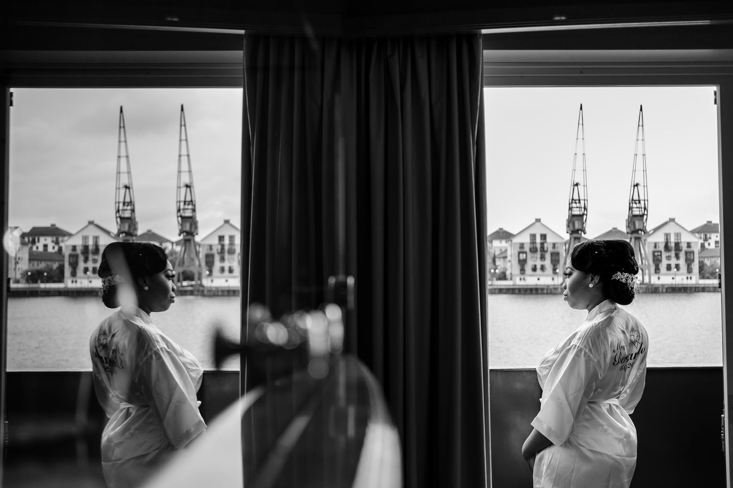 Black and white reflection shot showing church spires through curtained windows.