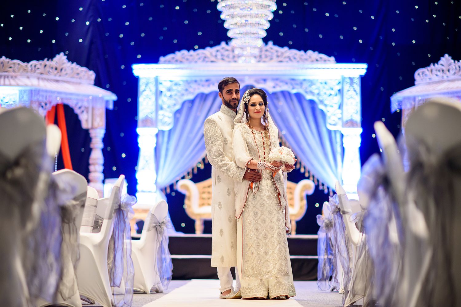 Elaborate blue and white wedding stage setup with illuminated backdrop and ornate decor.