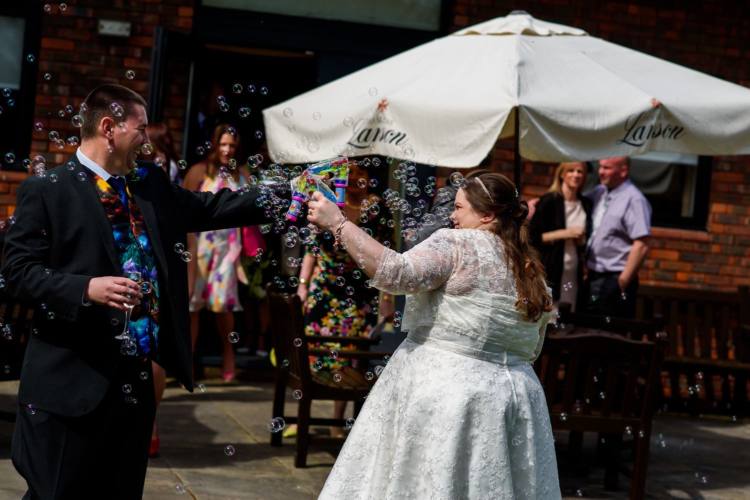 Wedding party gathering under white outdoor tents and umbrellas.