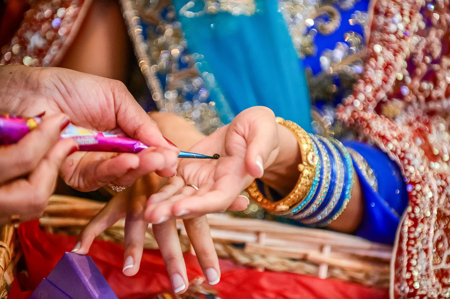 Traditional Indian wedding ceremony with colorful bangles and jewelry details being placed on hands.