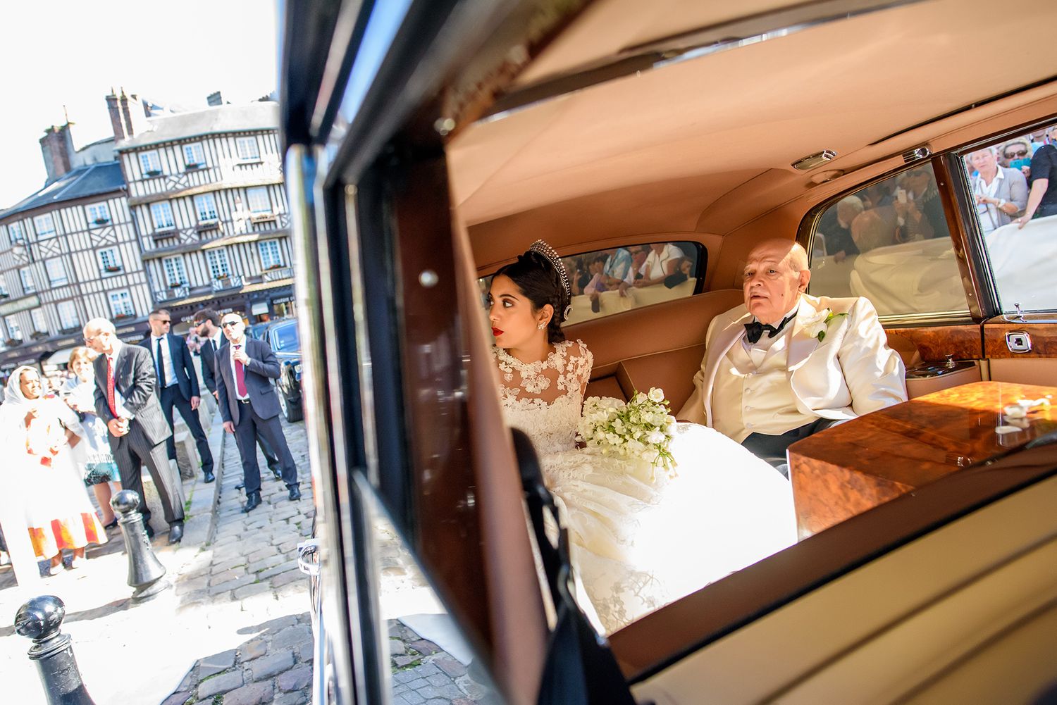 Elegant wedding ceremony venue with decorative hanging floral arrangements and guests seated in wooden chairs.
