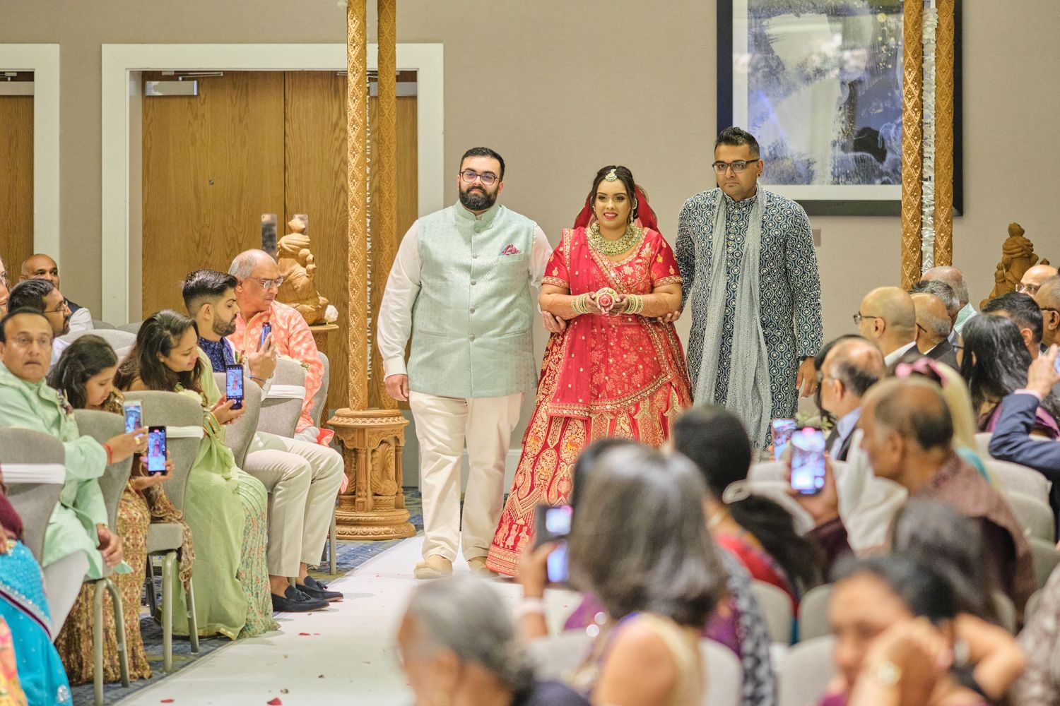 Guests seated in rows at an elegant indoor wedding ceremony with ornate decor and lighting.