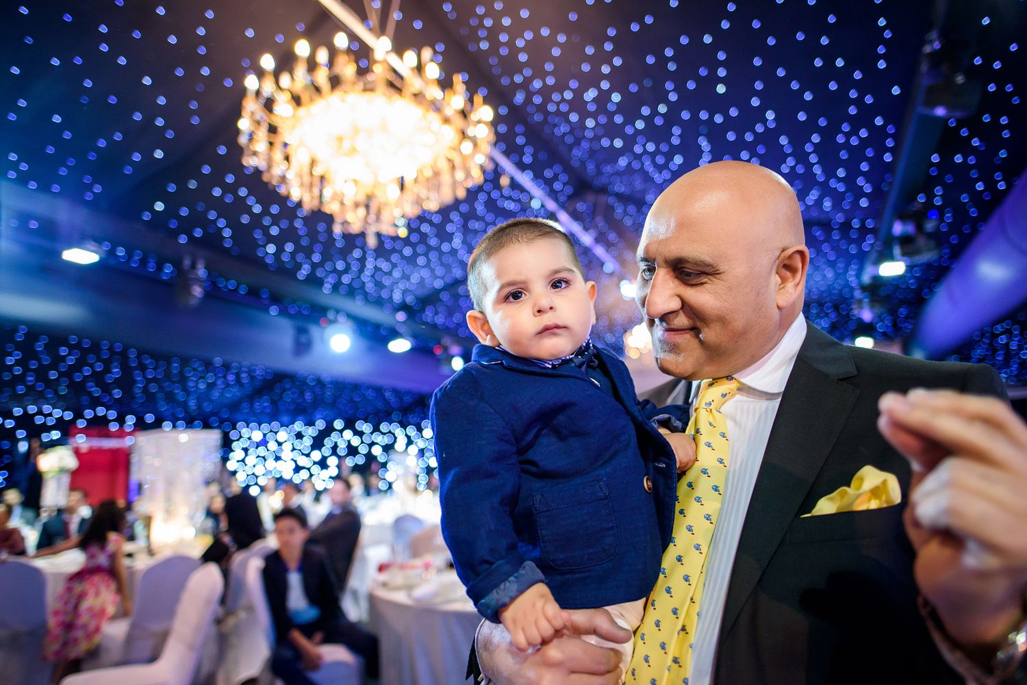 Wedding celebration under twinkling blue lights with chandelier overhead.