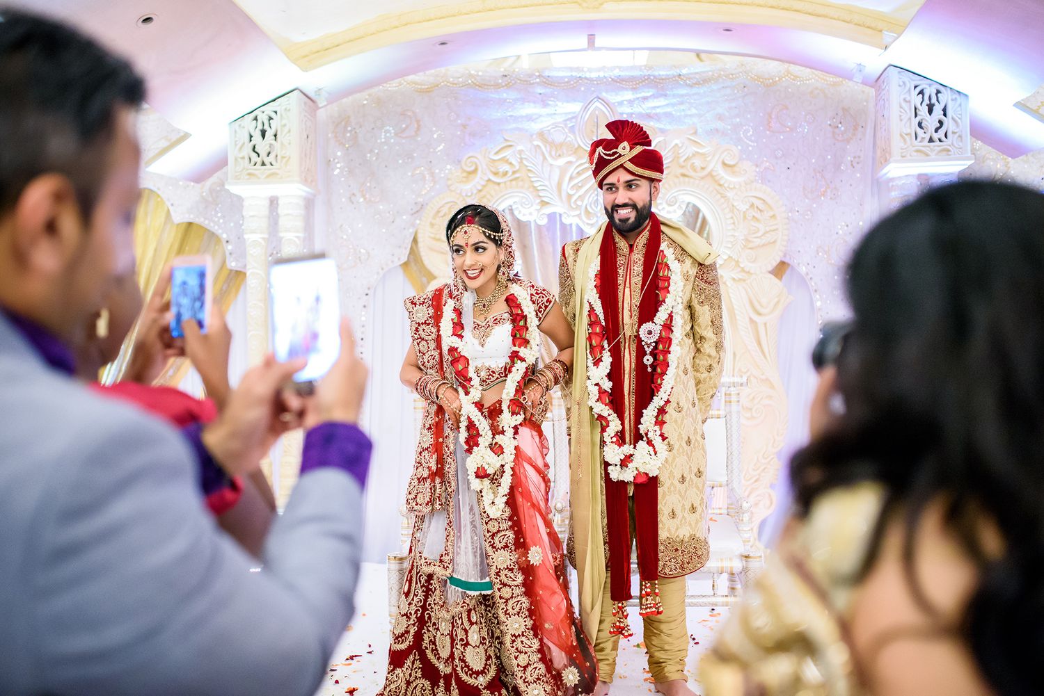 Ornate Indian wedding venue with elaborate gold and white decorations and lighting.