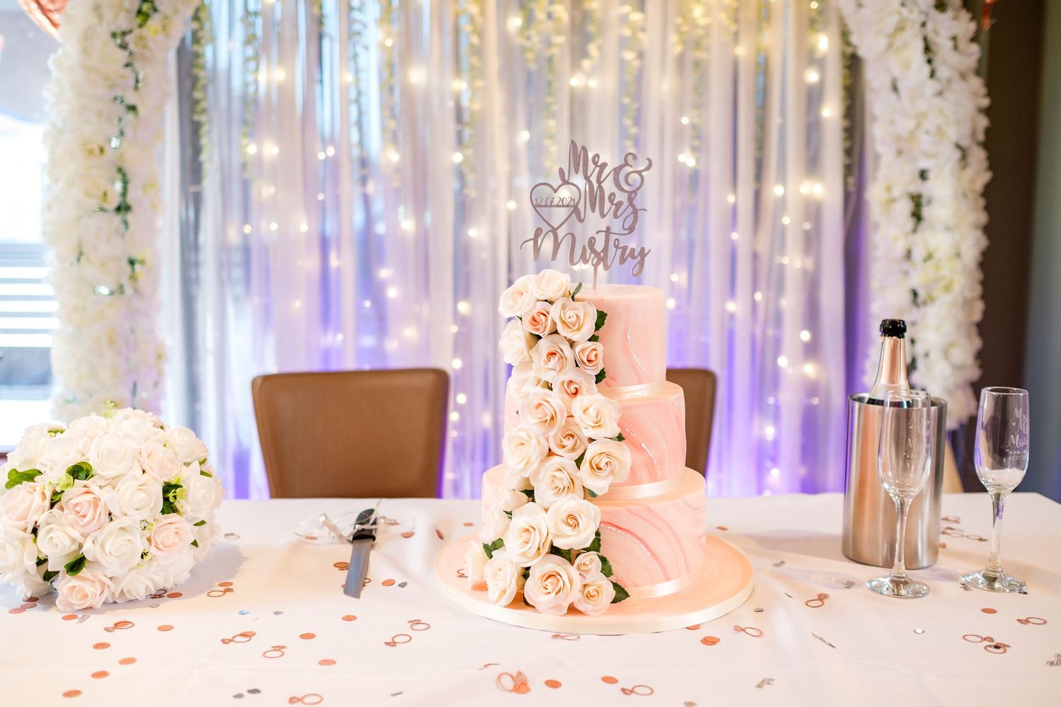 White floral wedding ceremony backdrop with twinkling lights and elegant decor.