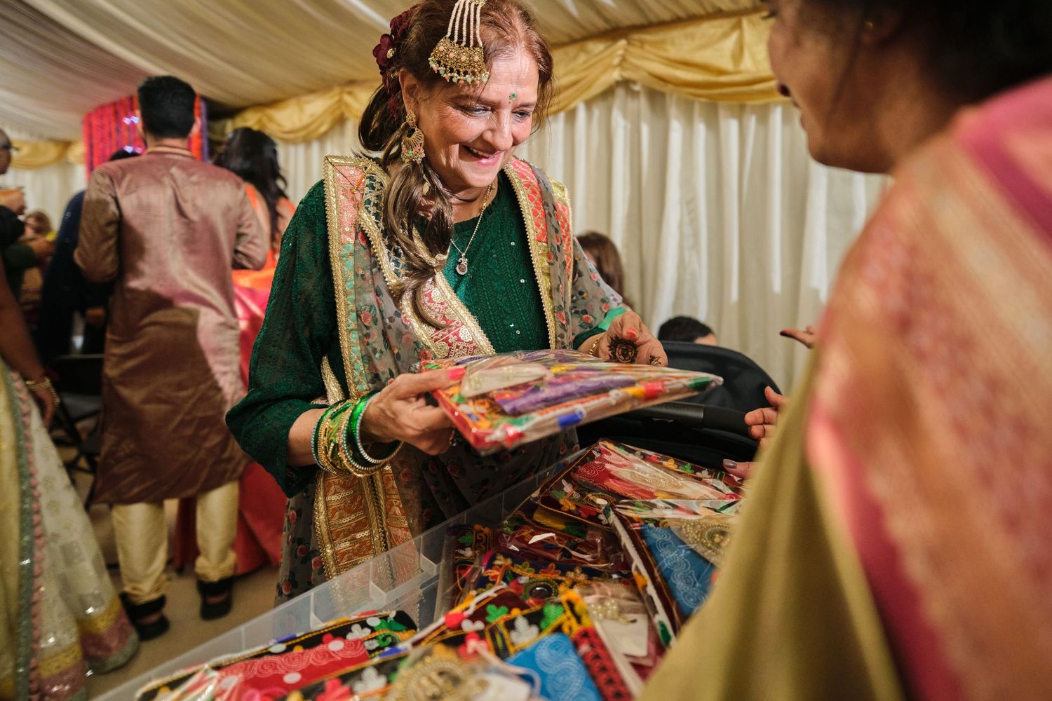 A person in traditional Indian attire examines colorful items at a cultural marketplace or celebration event.