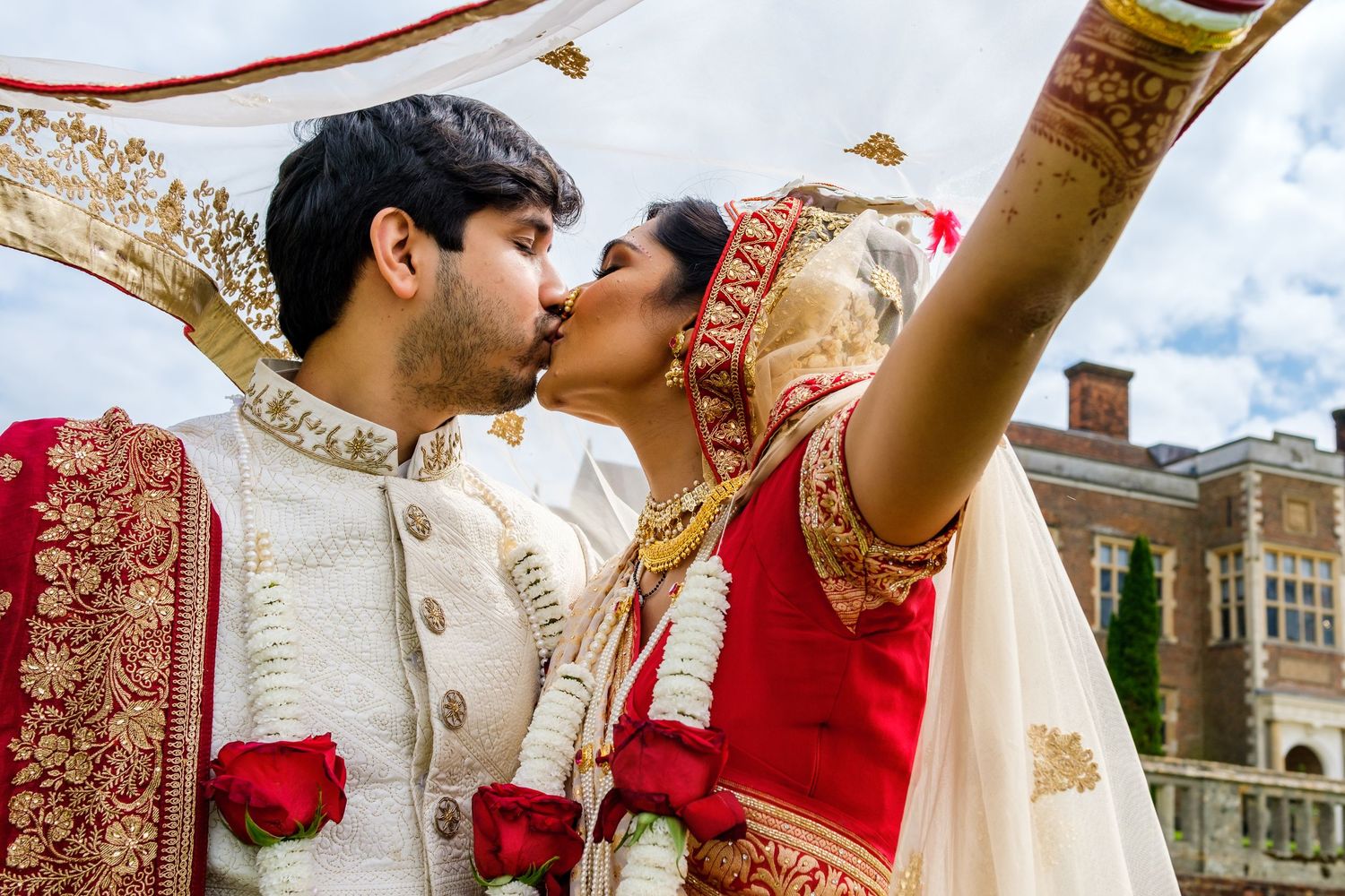 Romantic moment captured between newlyweds in traditional Indian wedding attire against historic architecture.