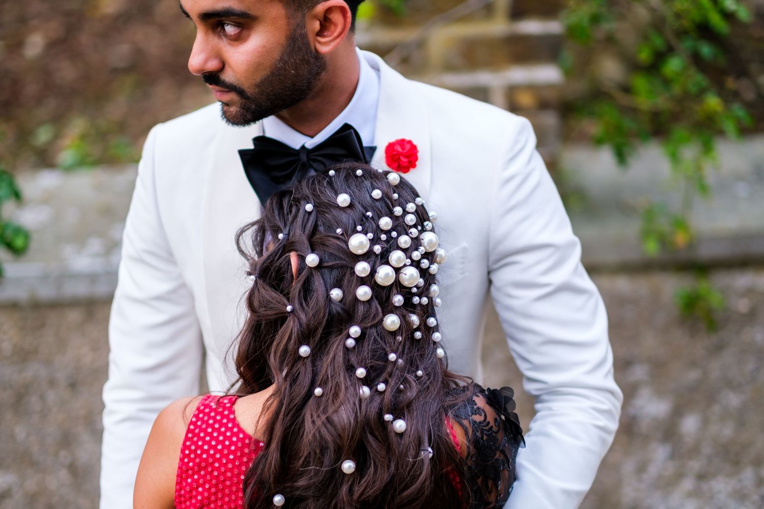 Wedding couple in formal attire with decorative floral and pearl hair accessories.