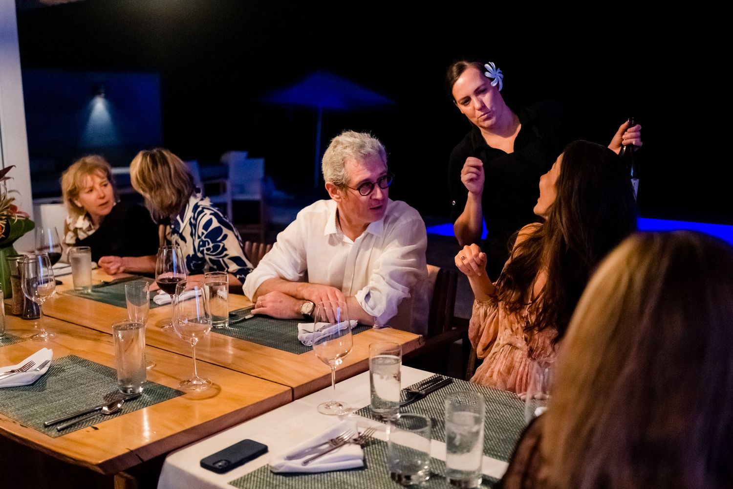 Guests gathered around a dimly lit restaurant table for dinner.