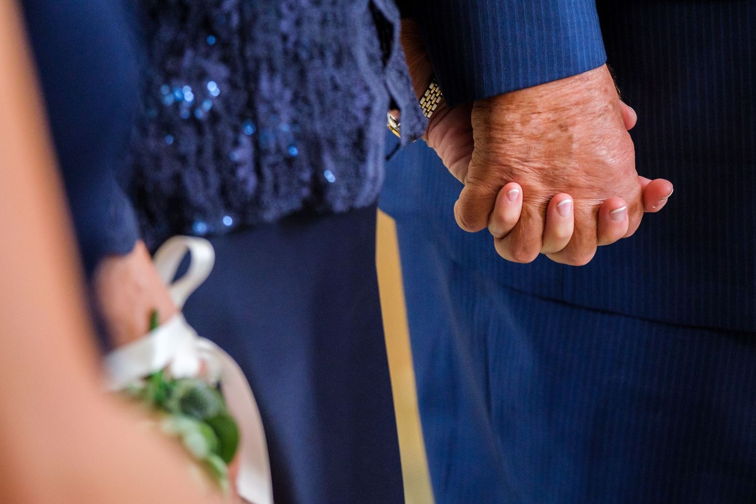Close-up of two hands clasped together with one person wearing a navy blue sleeve.