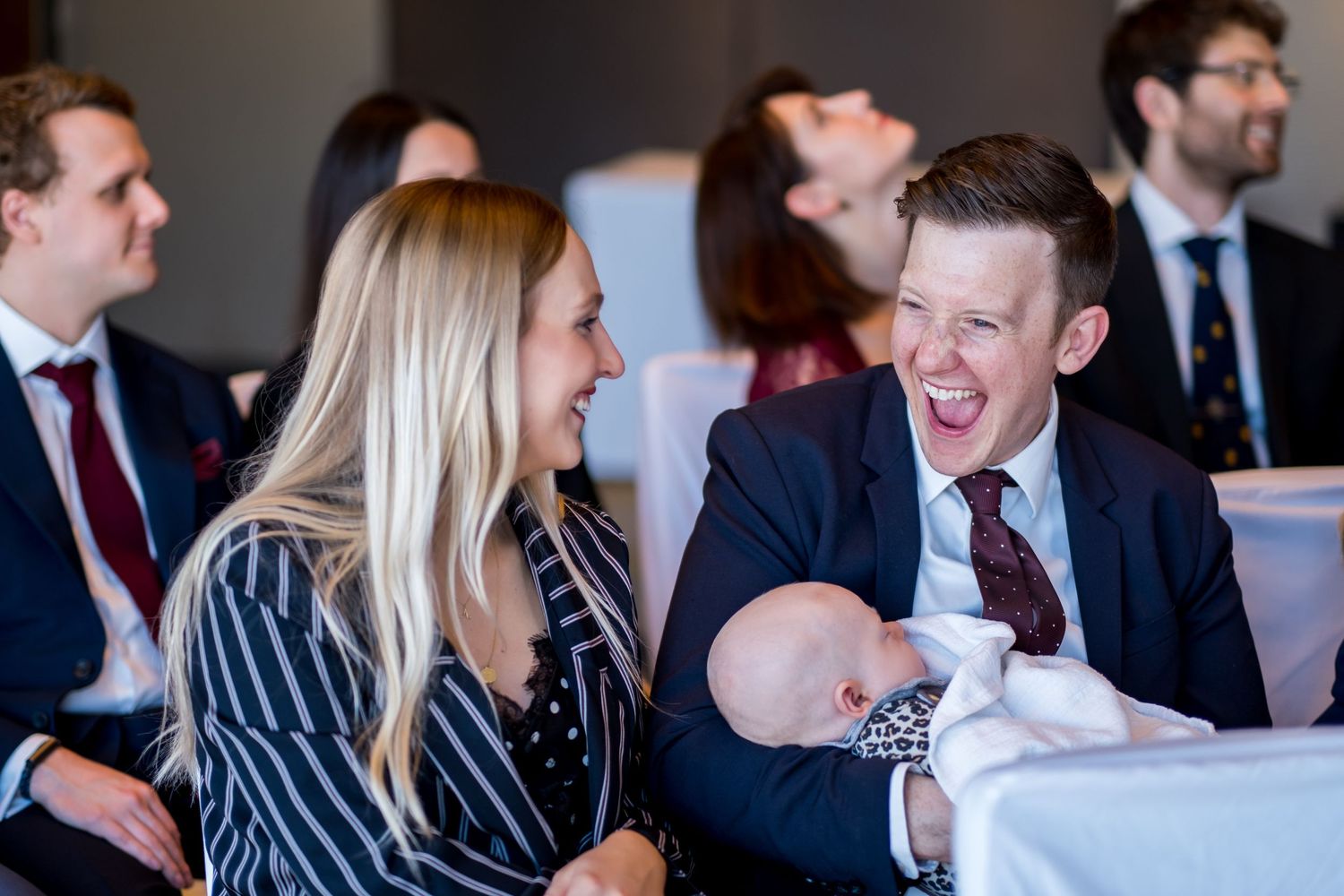Business professionals engage in animated conversation during a networking event in a bright modern setting.