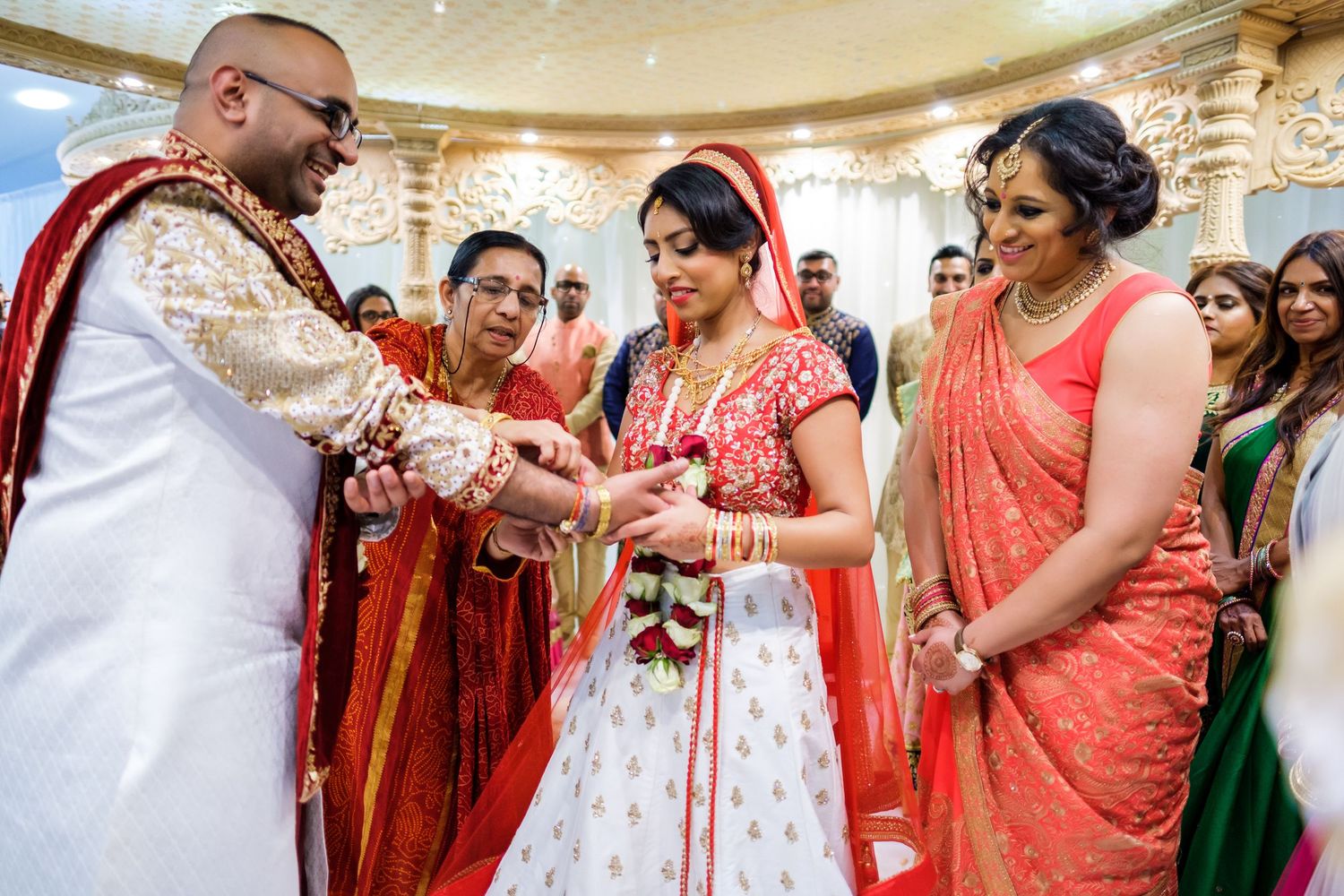 Traditional ring exchange ceremony during an Indian wedding with guests watching.