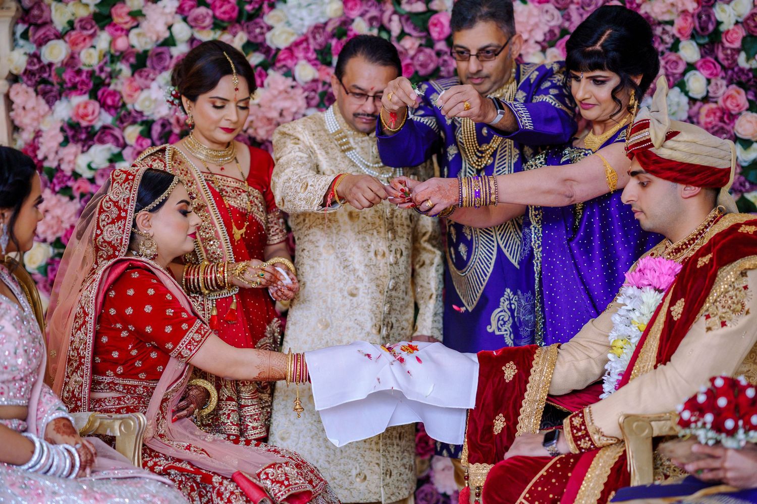 Celebratory moments at an Indian wedding with pink floral backdrop and traditional attire.