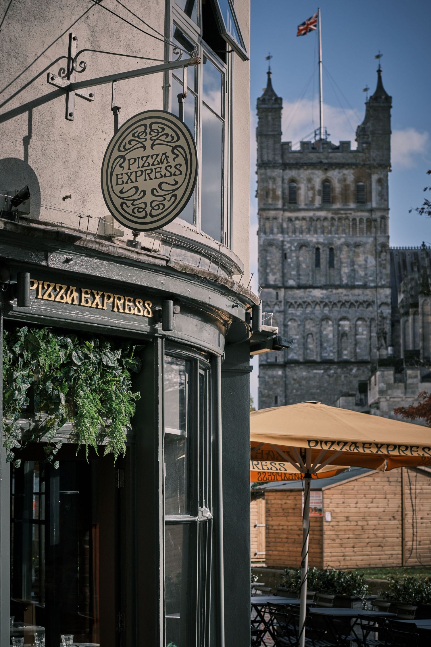 Historic stone building exterior with Pizza Express signage and classic architectural details against blue sky.