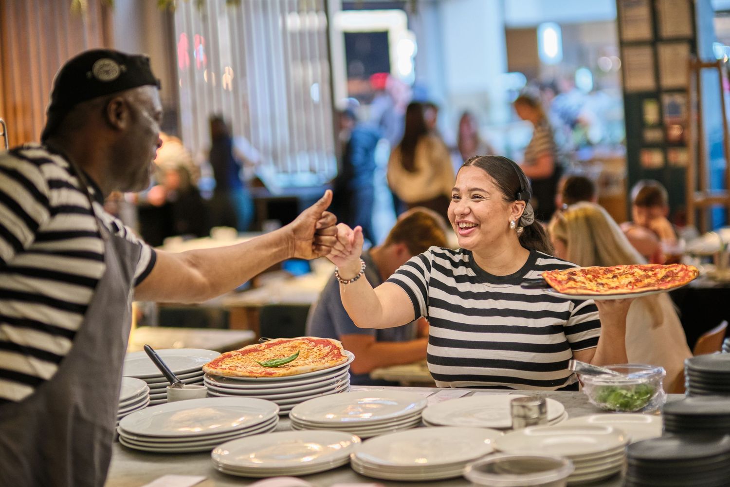 A group of people enjoying pizza and conversation at a casual restaurant gathering.
