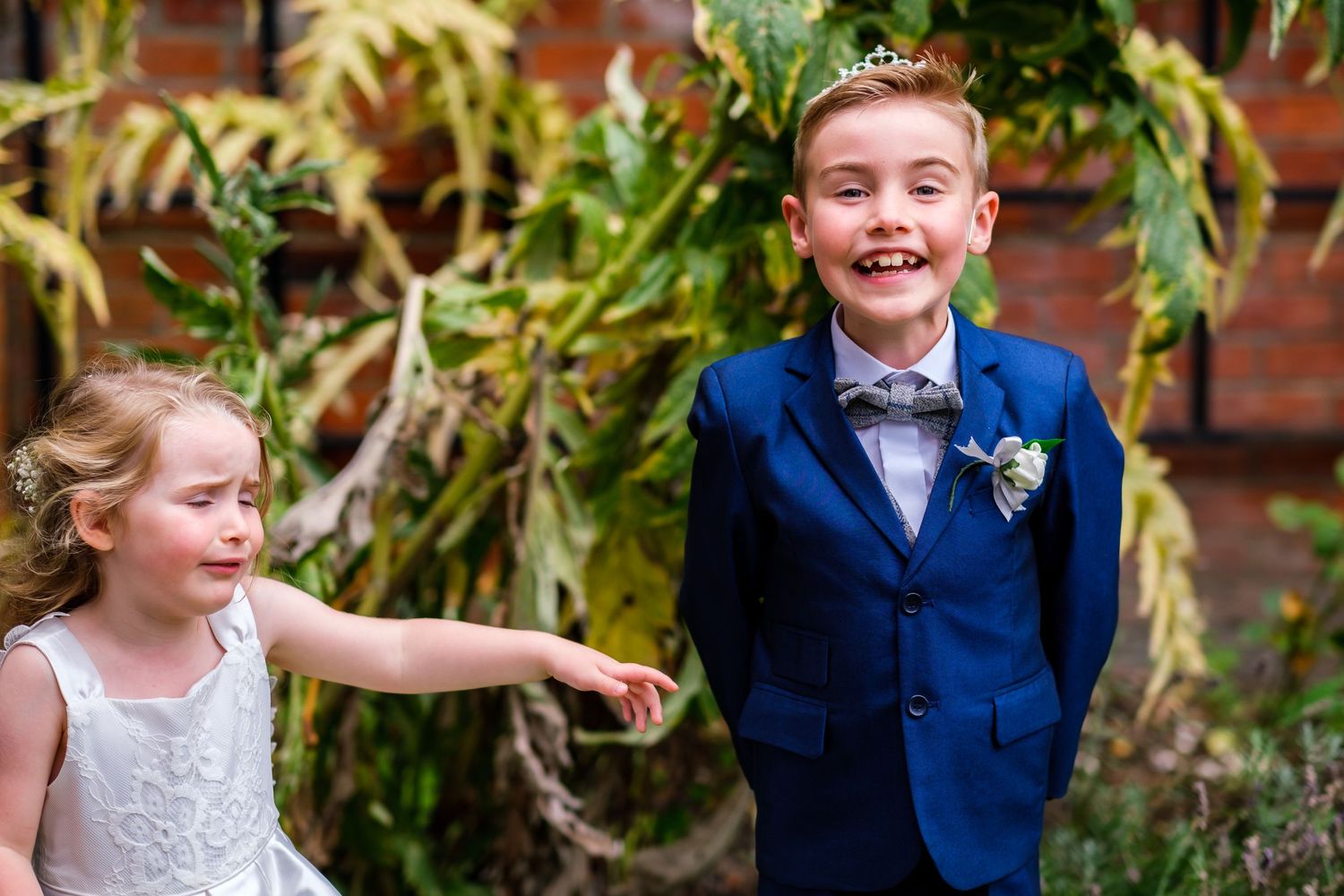 Children in formal attire smiling and playing during outdoor wedding festivities.