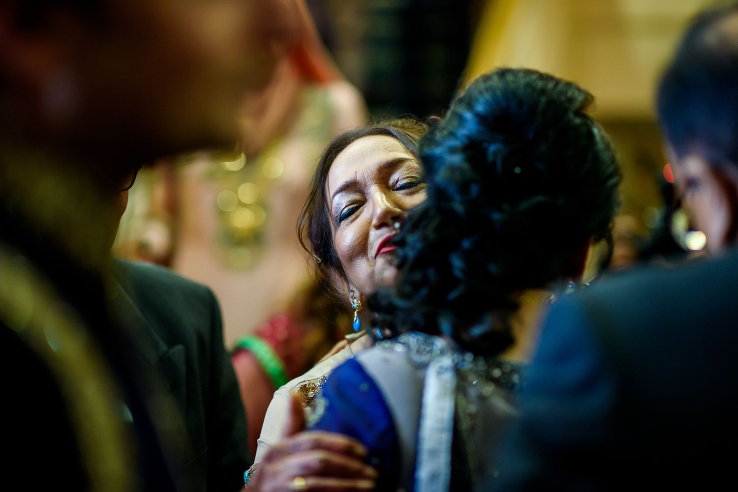 Guests celebrate joyfully at a festive wedding reception with colorful lighting and decor.