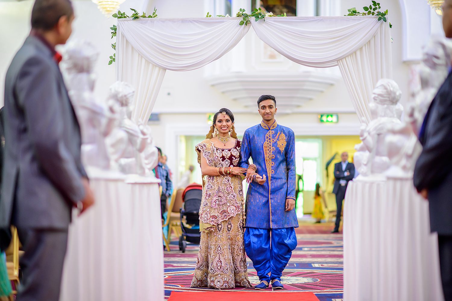 Traditional Indian wedding ceremony with vibrant decor and elegant white drapery in the background.