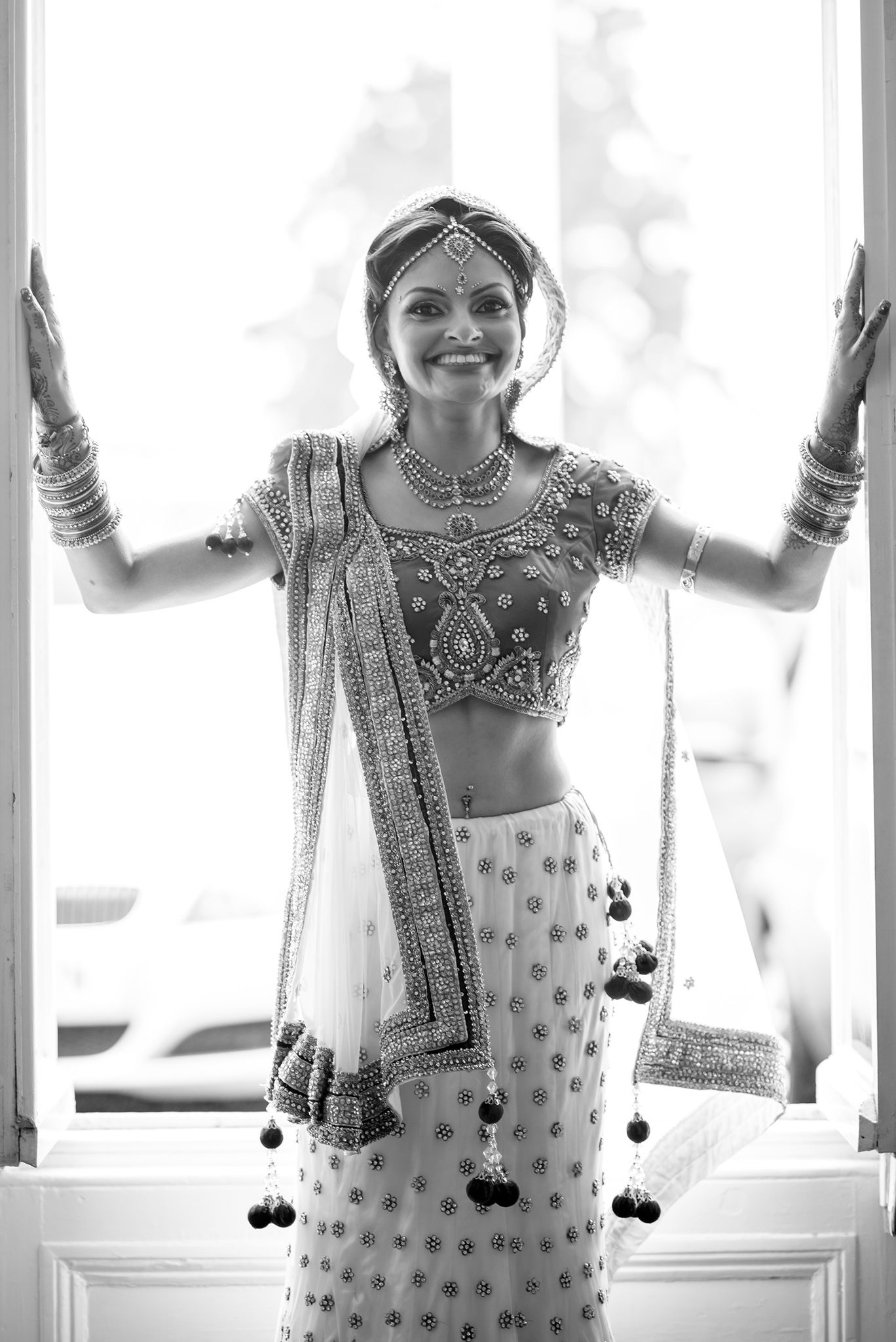 Artistic black and white sequence showing traditional Indian bridal preparations near a window.