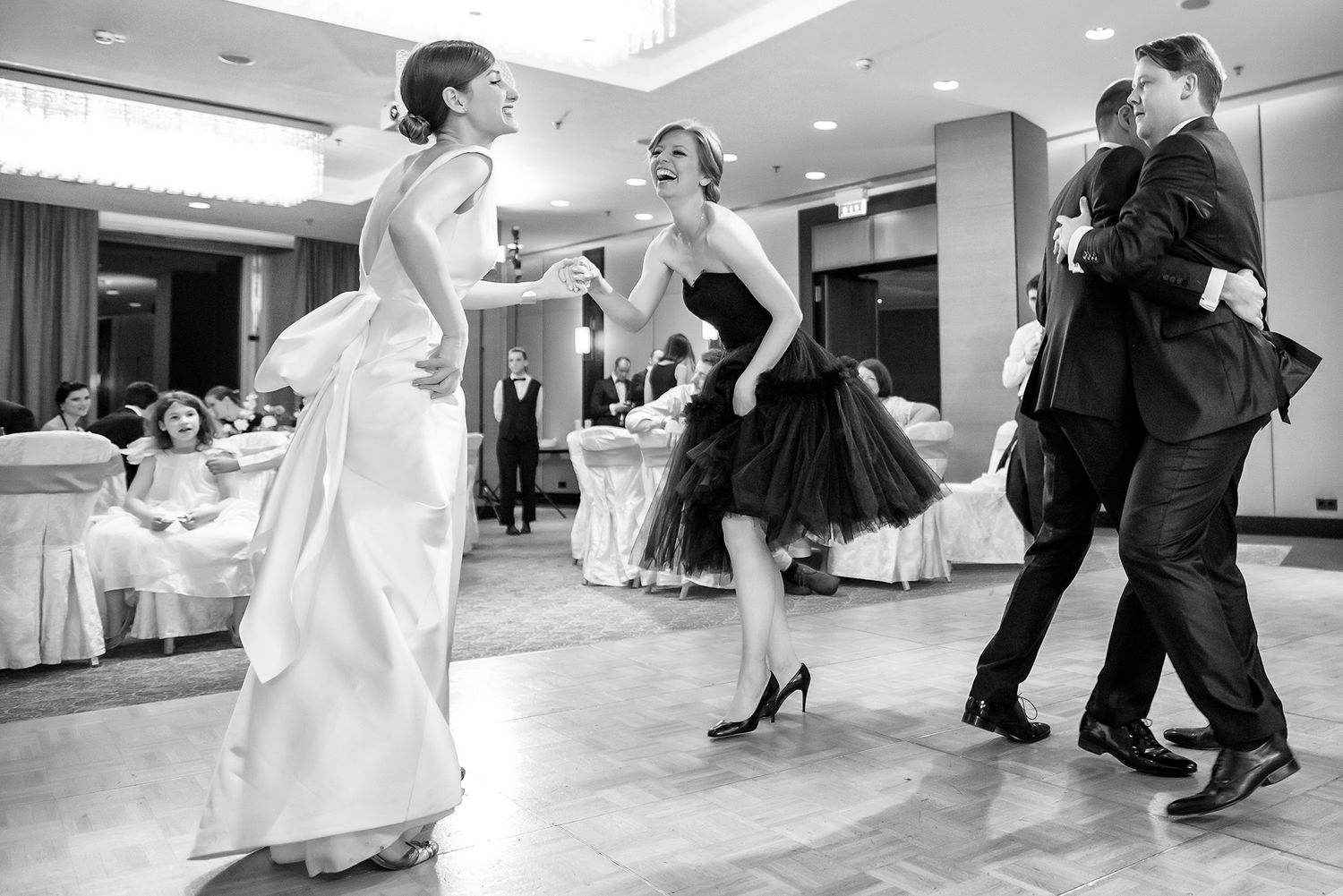 Couples dancing and celebrating at an indoor wedding reception.
