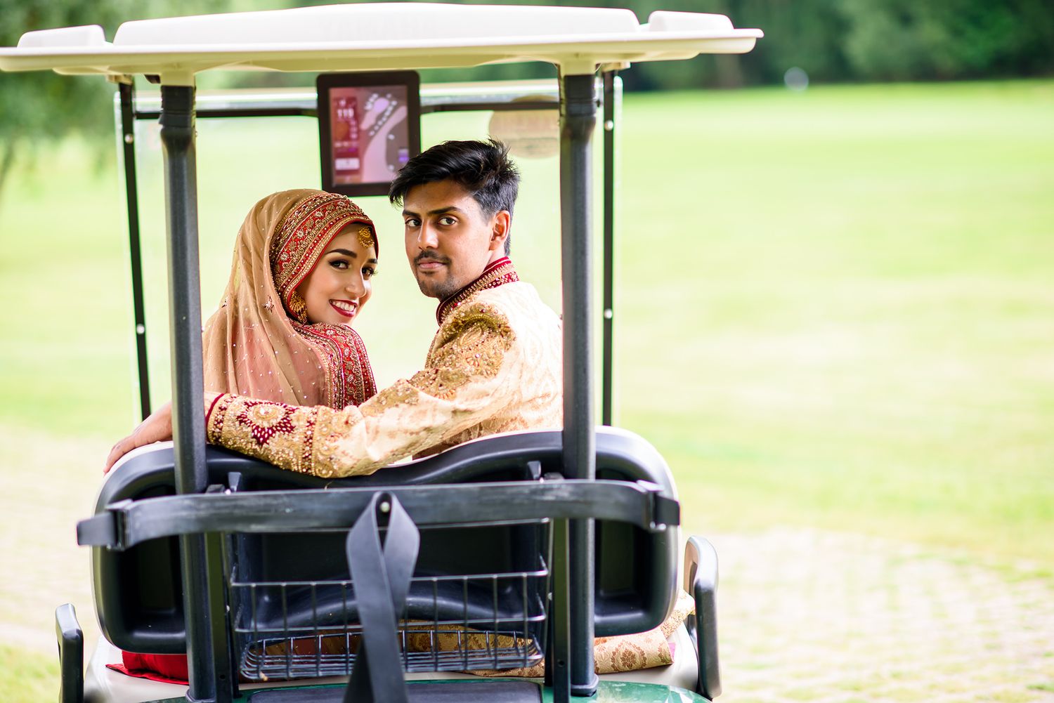 Wedding couple poses in golf cart sequence on sunny green course.