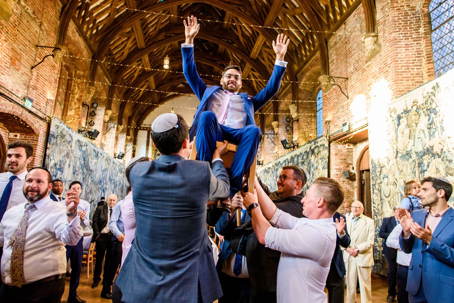 Wedding celebration inside a rustic brick venue with guests dancing and celebrating.