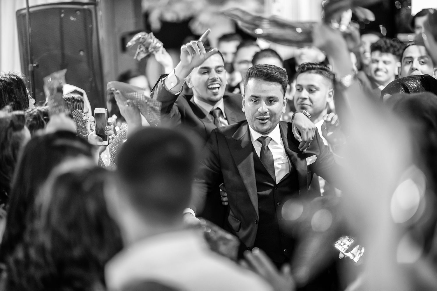 Black and white image of wedding guests dancing and celebrating.