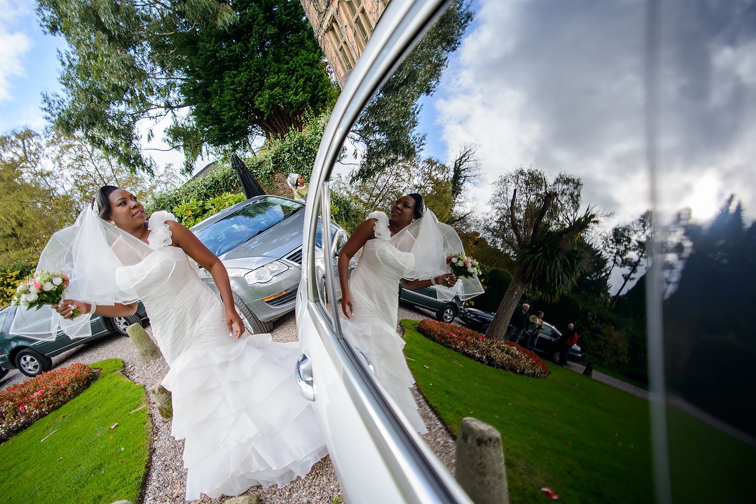 Wedding party poses around a classic white car on a sunny day.