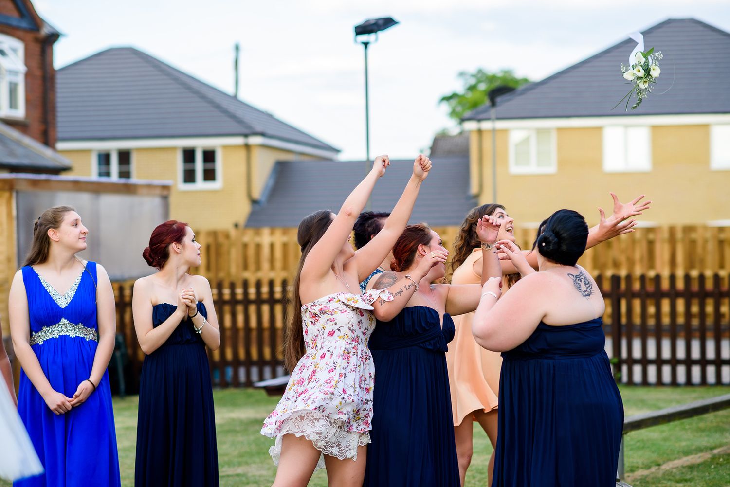 Celebration outdoors with guests in navy dresses against suburban houses.