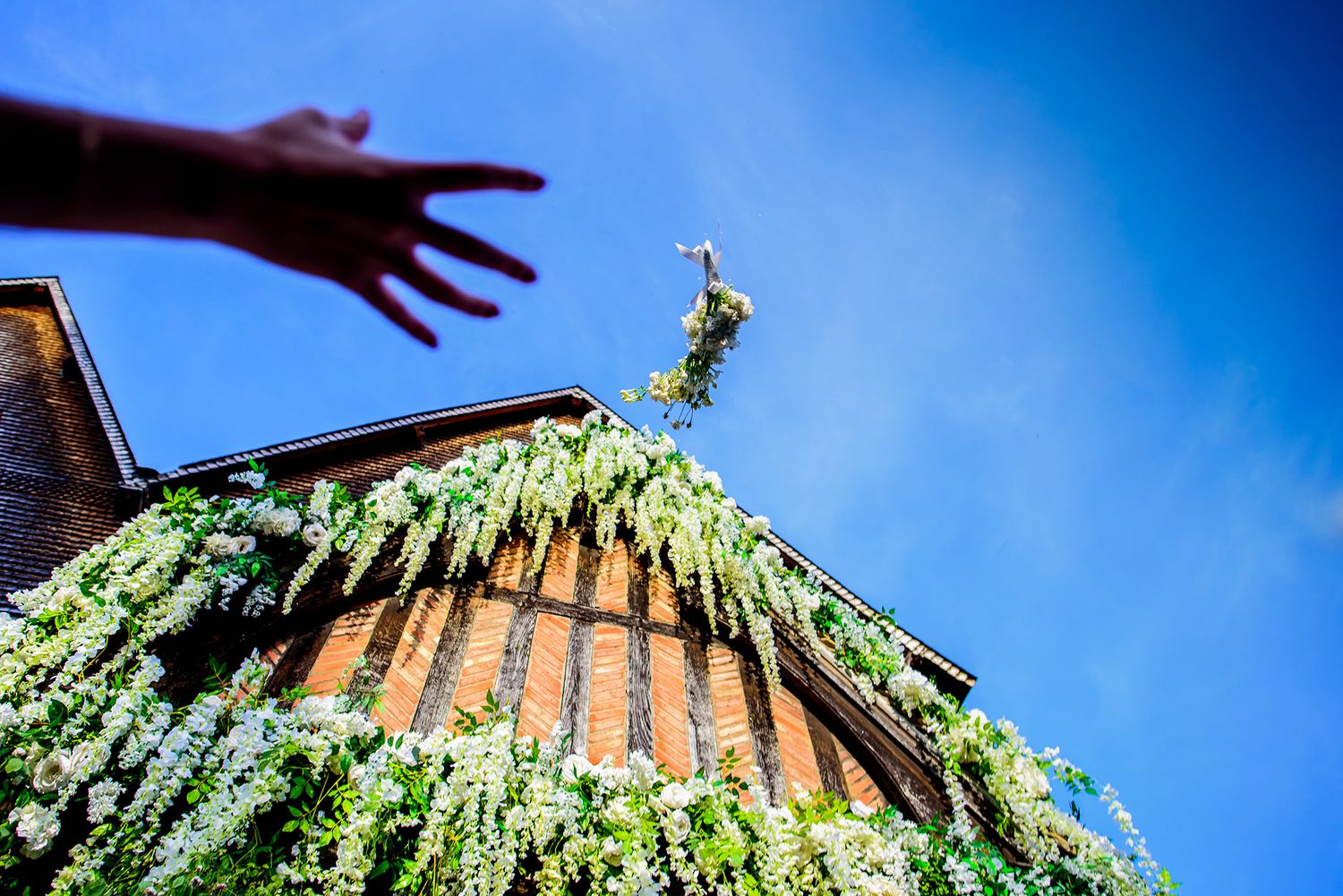 Upward view of Gothic church architecture against blue sky with hanging greenery decorations.