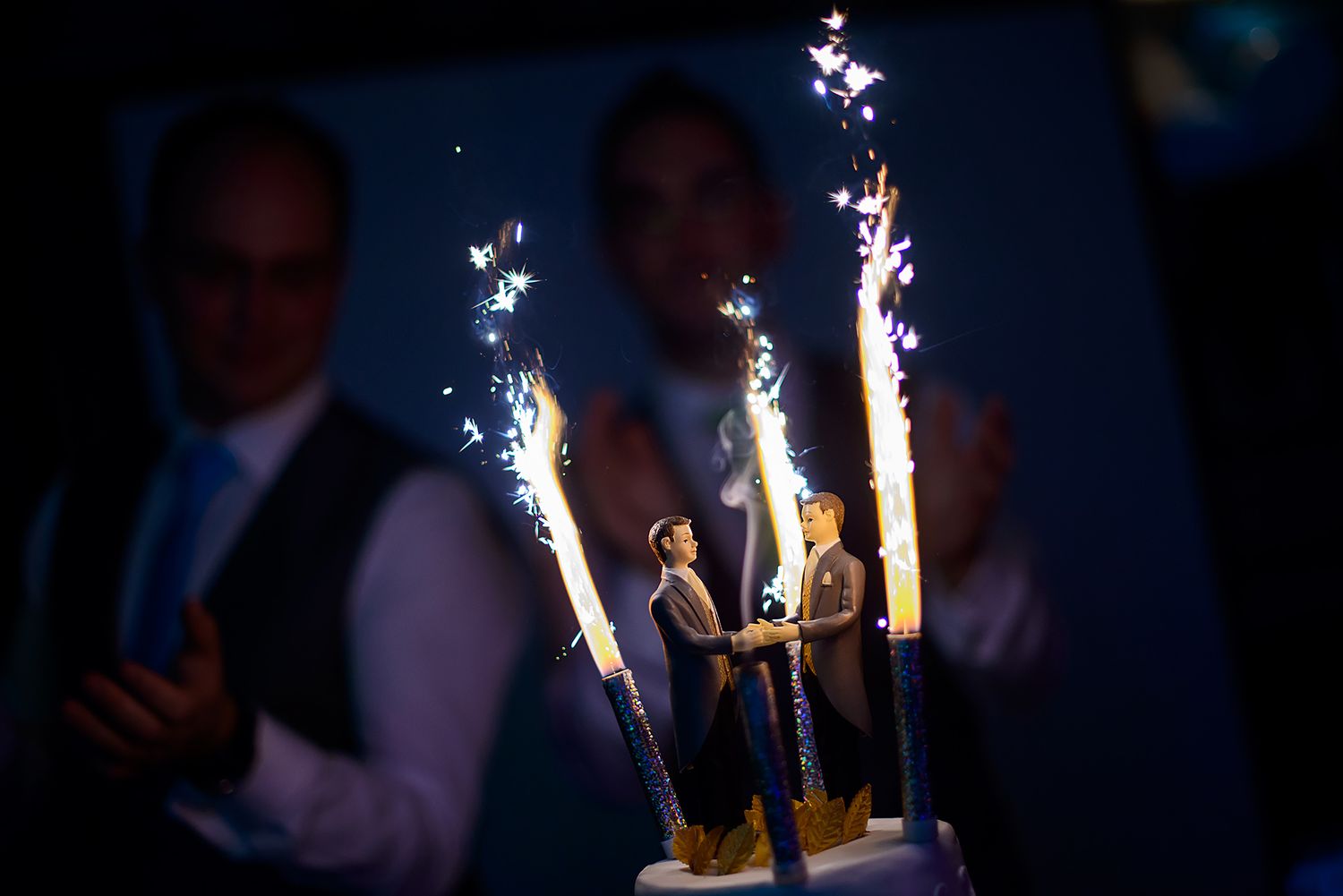 Sparklers illuminate dark reception venue creating dramatic celebratory atmosphere.