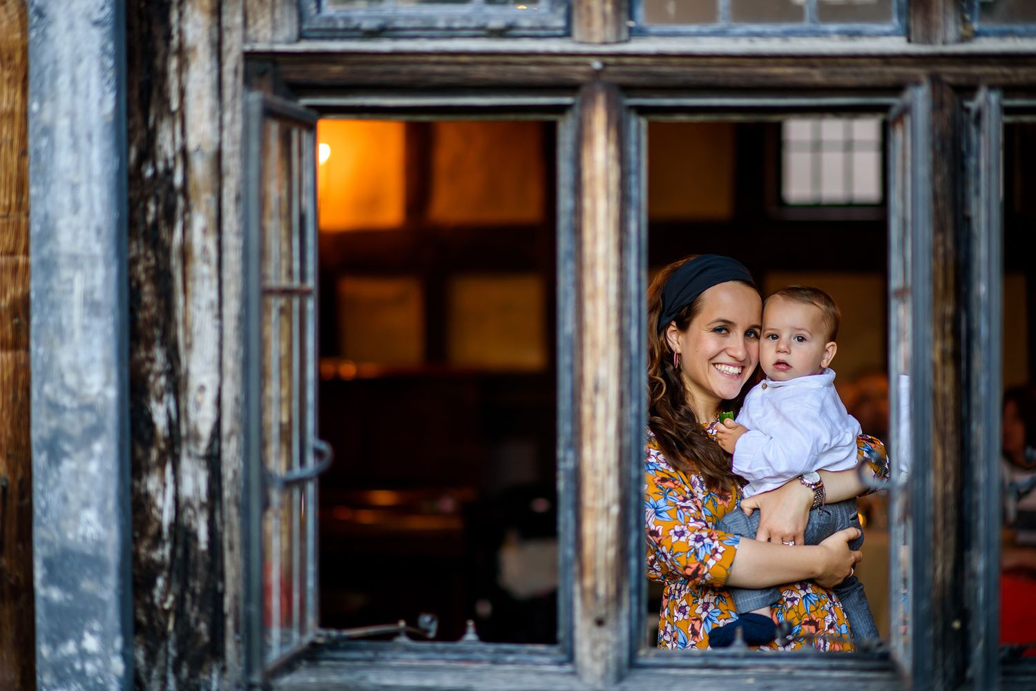 Guests interact through large vintage windows of a historic building during a celebration.