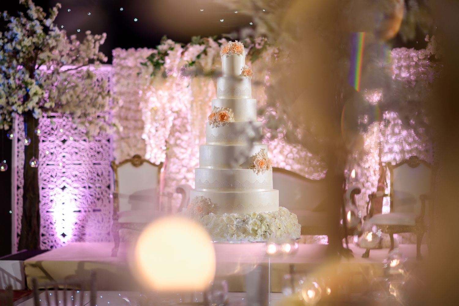 Wedding venue decorated with pink cherry blossoms and ambient lighting.