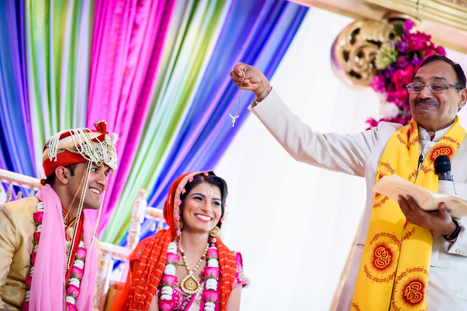 Festive Indian wedding ceremony under colorful draped fabric decorations.
