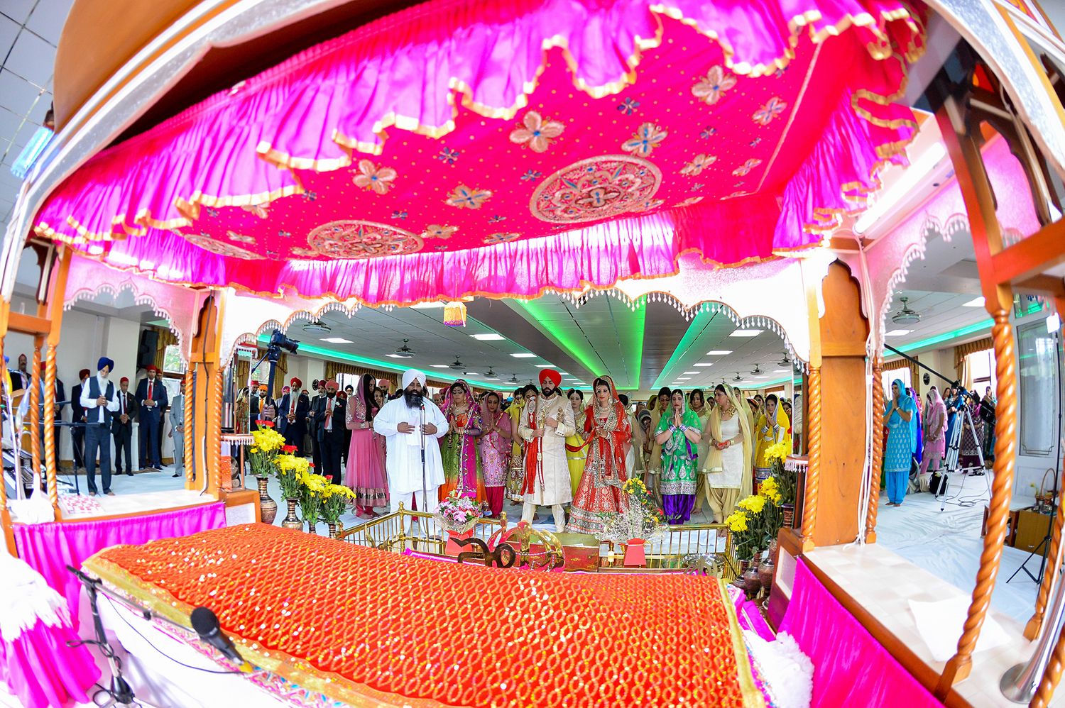 Vibrant pink and orange wedding mandap decorated for traditional Indian ceremony.