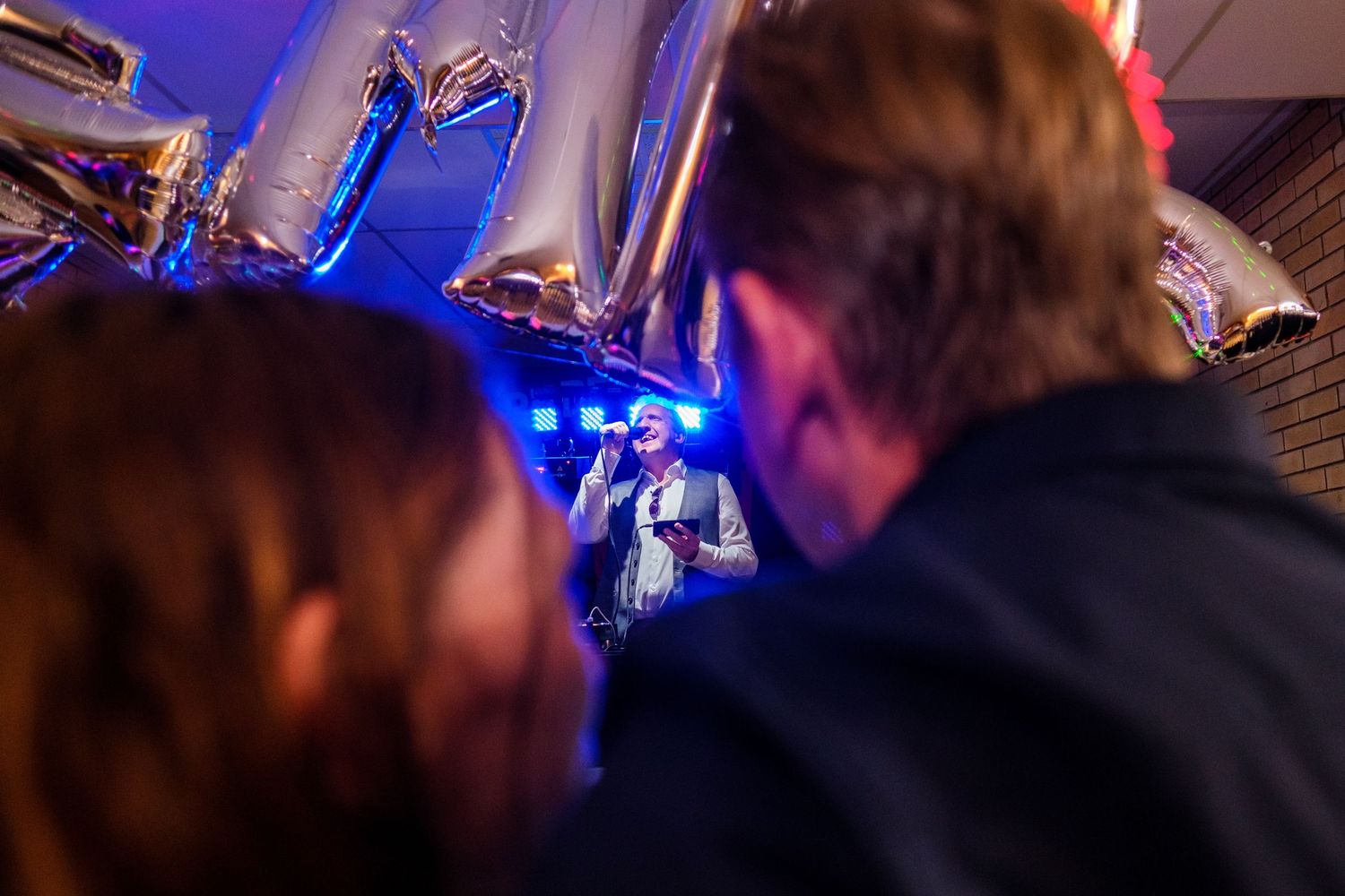 Guests enjoying live entertainment at a dimly lit wedding reception with blue stage lighting.