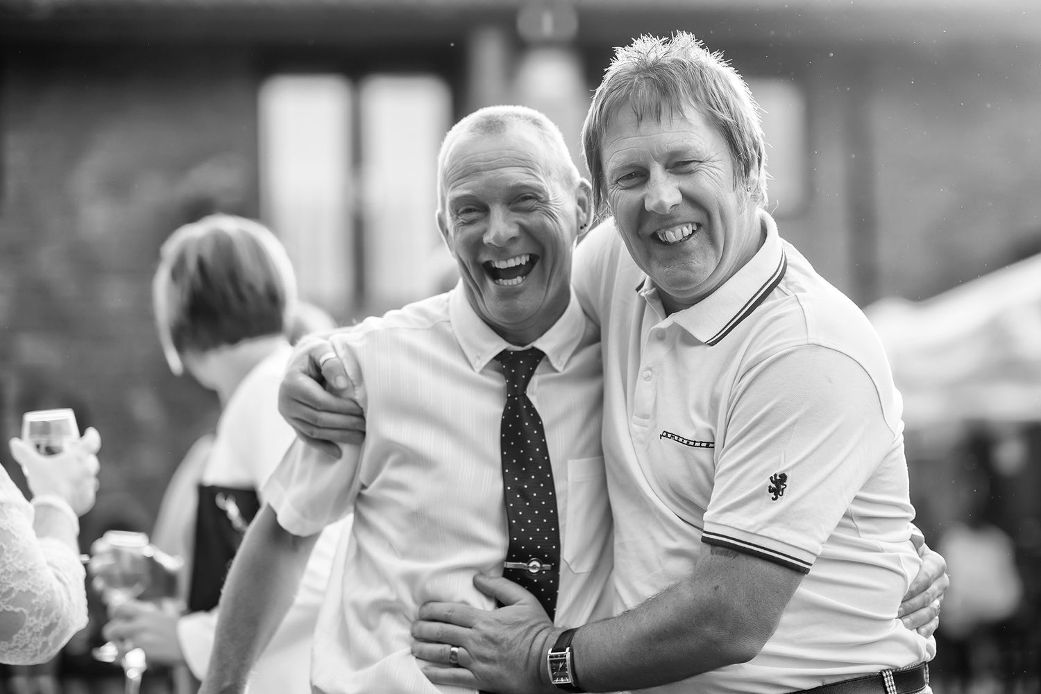 Black and white candid shot of wedding guests sharing laughter.