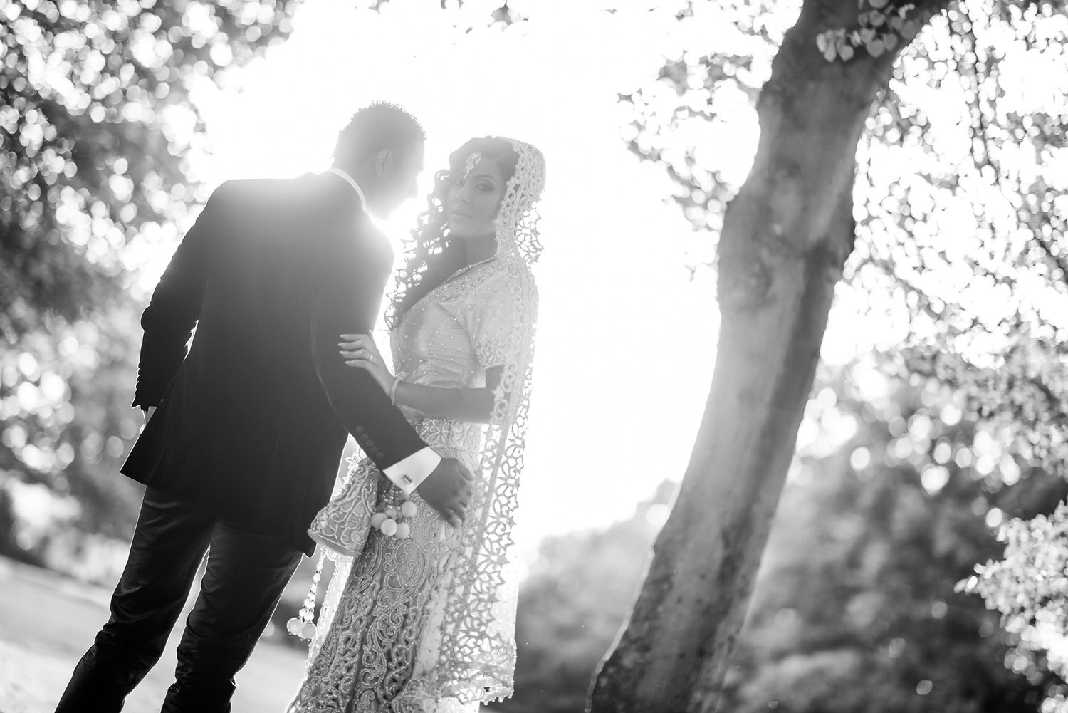 Silhouetted figures walking among trees with dramatic sunlight filtering through branches.