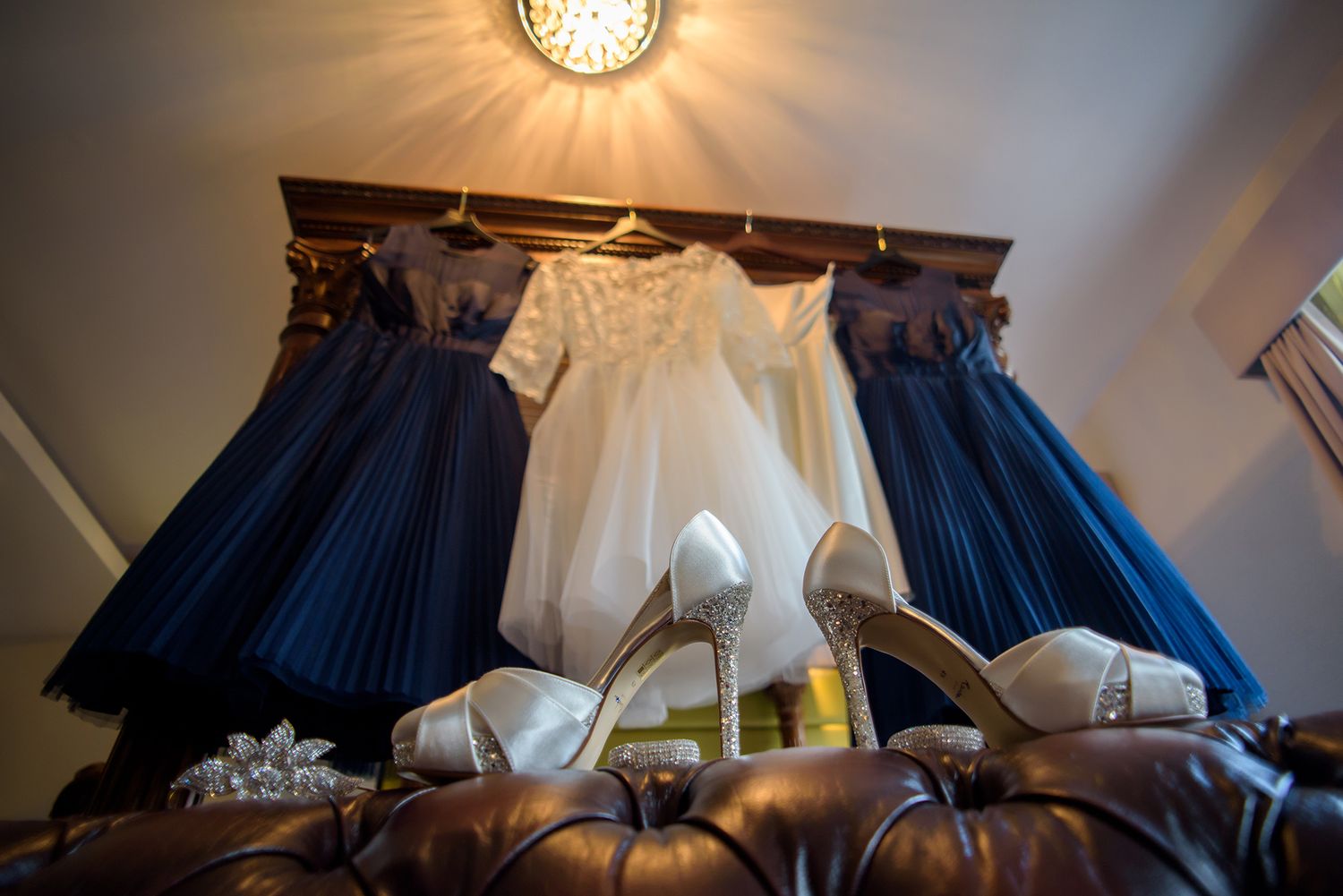 Row of blue and white bridesmaid dresses hanging beneath an elegant chandelier.