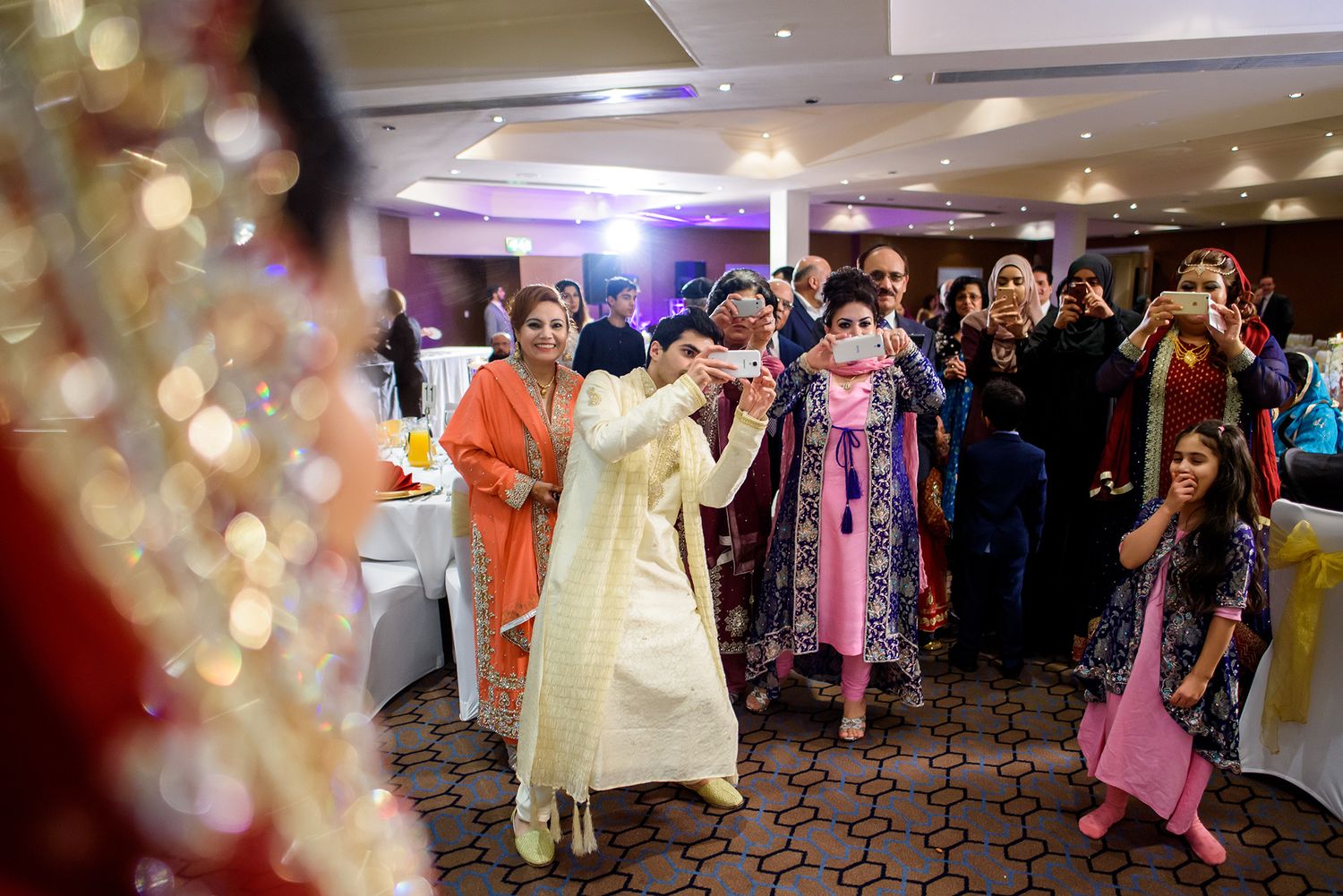 Wedding reception celebration with guests dancing under colorful lights.