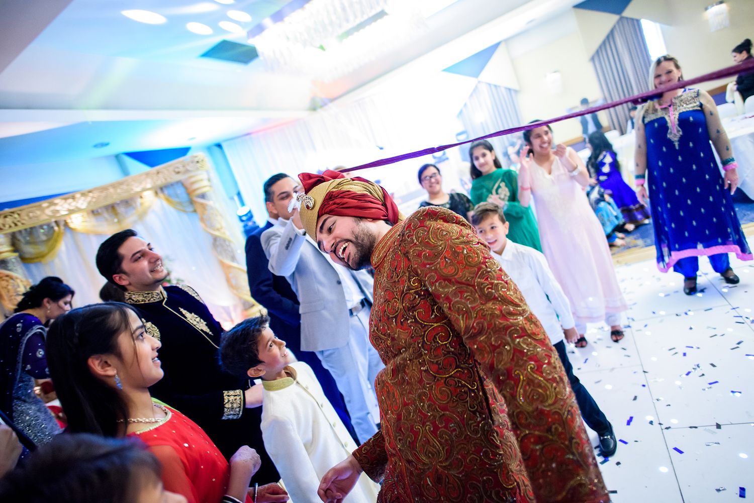 Wedding reception party with guests dancing and confetti in an indoor venue.