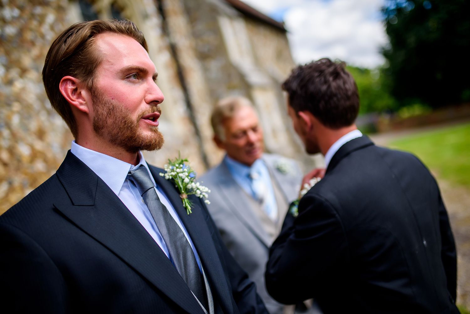 Formal group gathering outside a stone building during wedding festivities.
