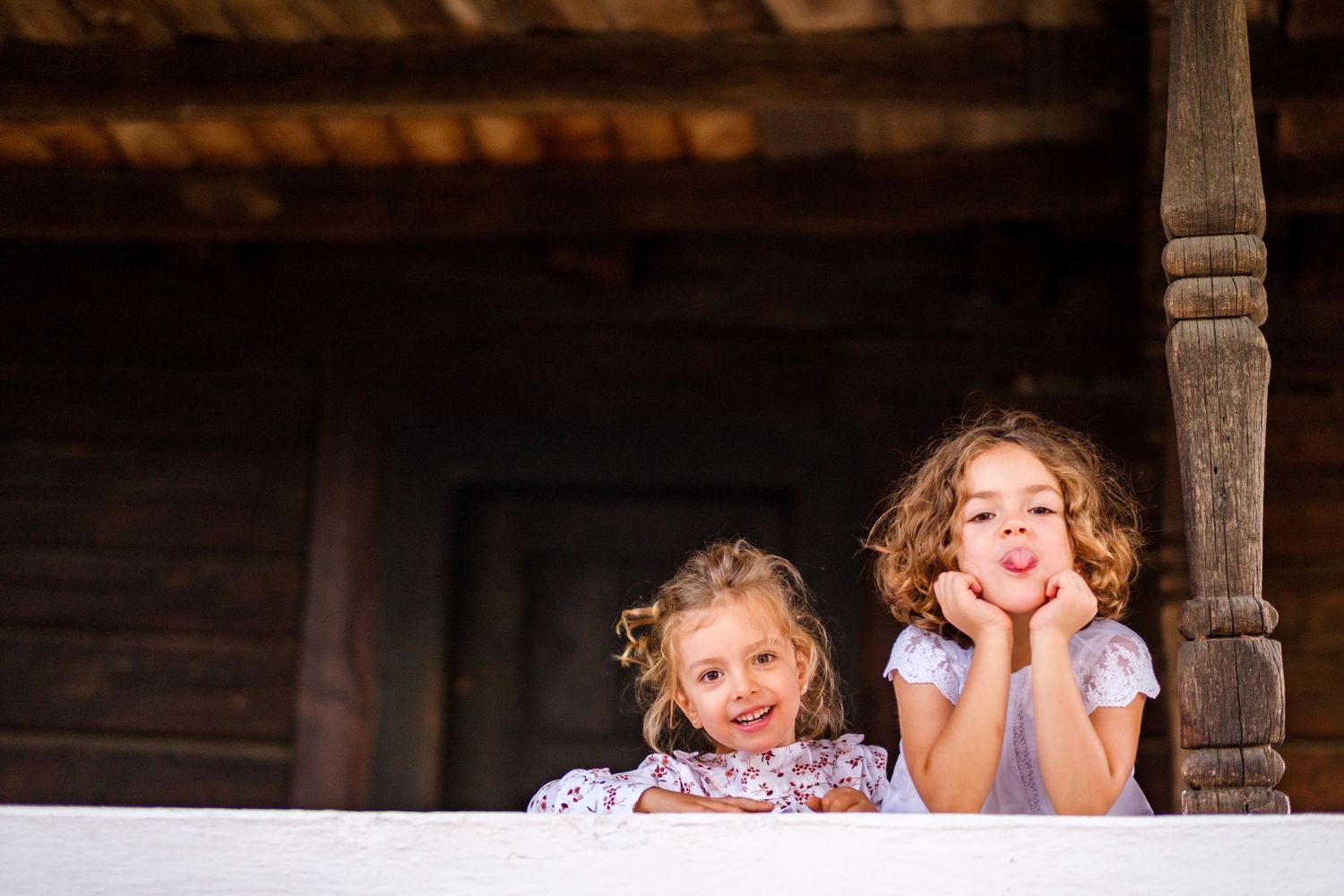 Children enjoying playful moments under wooden beams of rustic porch setting.