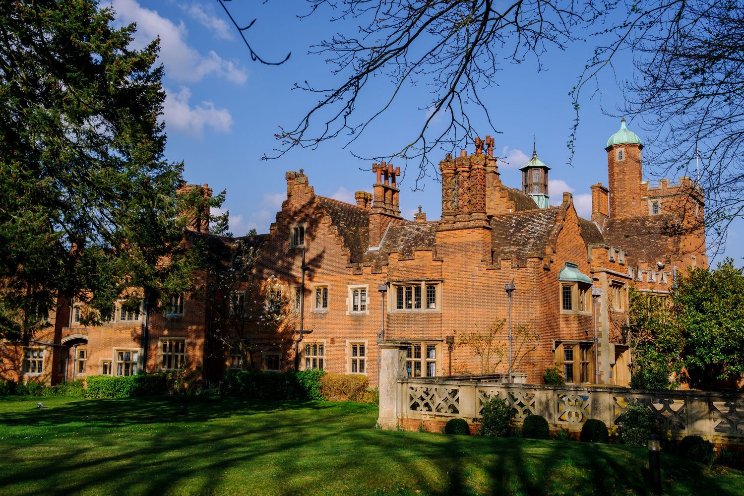 Exterior view of a historic red brick manor house with multiple chimneys and architectural details.