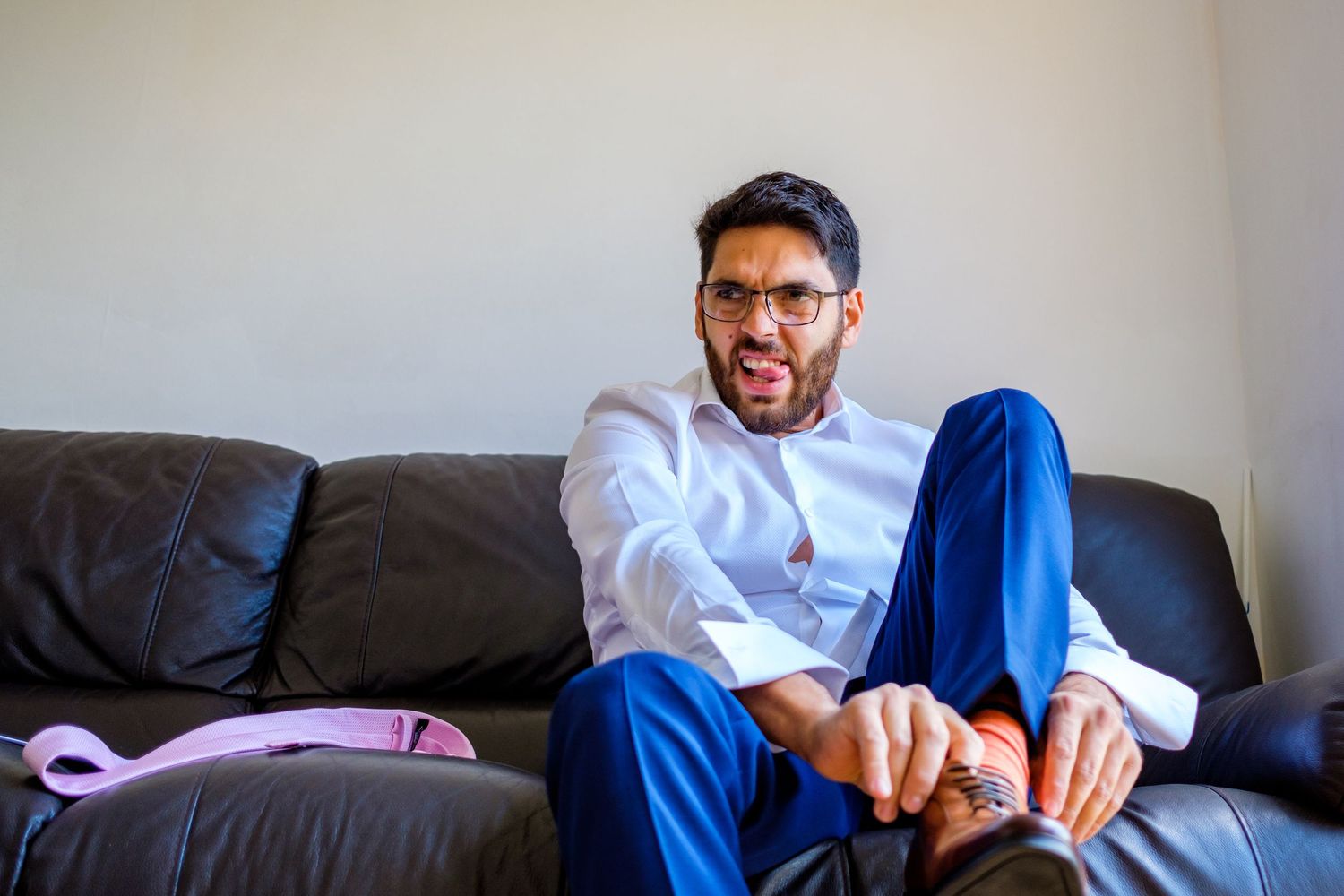 A person relaxes on a grey couch wearing casual clothing while looking at their phone.