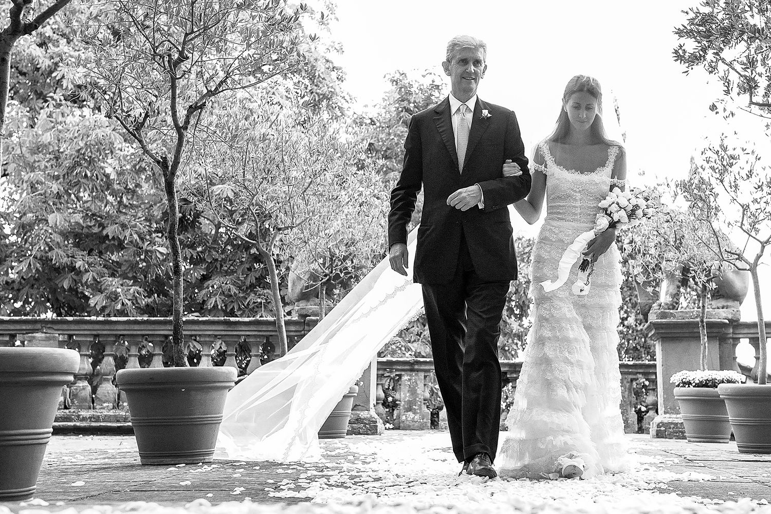 Wedding couple and guests walking through a beautiful outdoor garden venue.