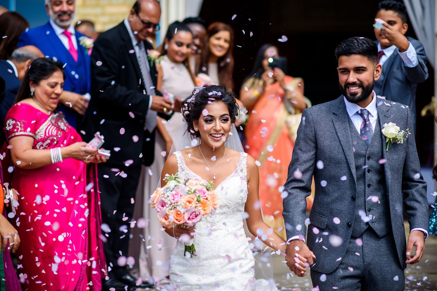 Celebratory moment as confetti fills the air around wedding party outside venue entrance.